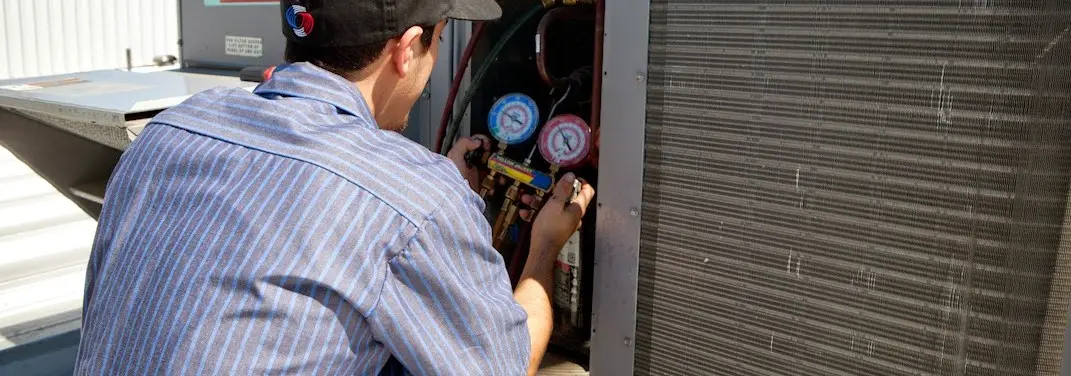 HVAC technician servicing a condenser unit in Ellettsville